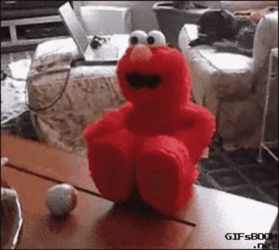 Red Elmo Stuffed Animal Sitting Next To Ball GIF