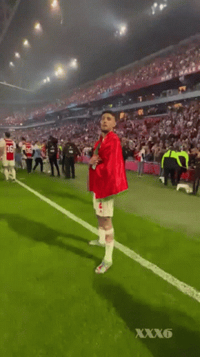 Red-Green Shirt Man Walking Soccer Field Crowd GIF