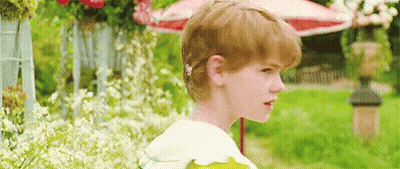 Red-Haired Boy With Flower In Garden GIF