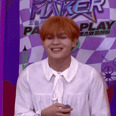 Red-Haired Man Holding Microphone In Front Of Checkered Wall GIF