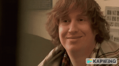 Red-Haired Man Smiling In Front Of Kapwing Sign GIF