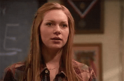 Red-Haired Woman At Chalkboard With Windblown Hair GIF