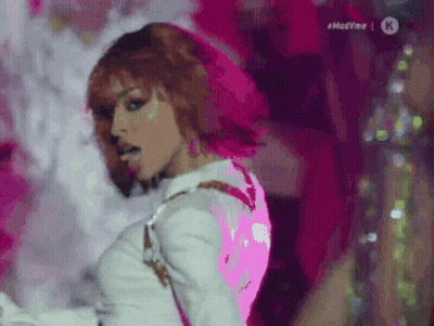 Red-Haired Woman Dancing Beside #Madvmo Sign GIF