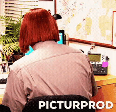 Red Haired Woman Sitting At Desk With Computer And Telephone GIF