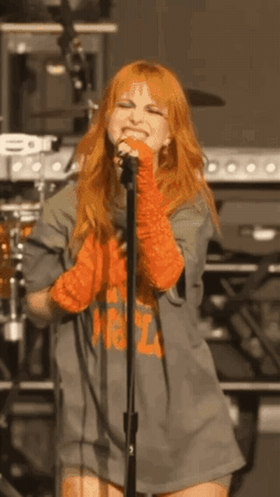 Red-Haired Woman Standing At Microphone On Stage GIF