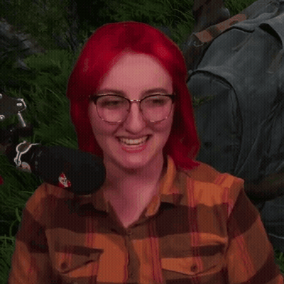 Red-Haired Woman With Glasses Sitting in Grass With Microphone