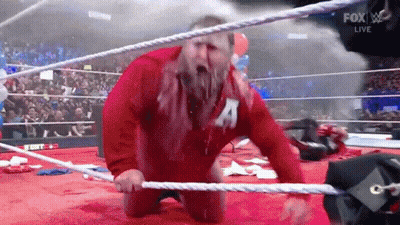 Red Jacket Man With 'A' Kneeling Wrestling Ring GIF