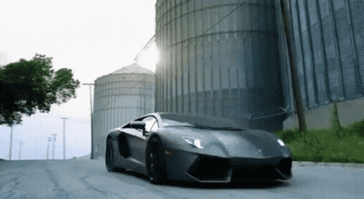 Red Robot With Horn Standing In Front Of Yellow Truck GIF