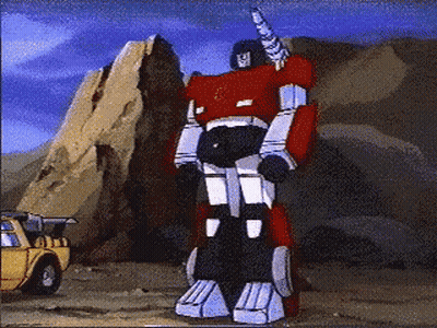 Red Robot With Horn Standing In Front Of Yellow Truck GIF