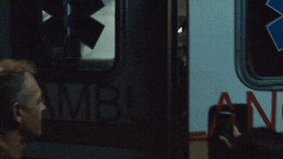 Red Shirt Man Holding Gun Beside Person In Wheelchair GIF