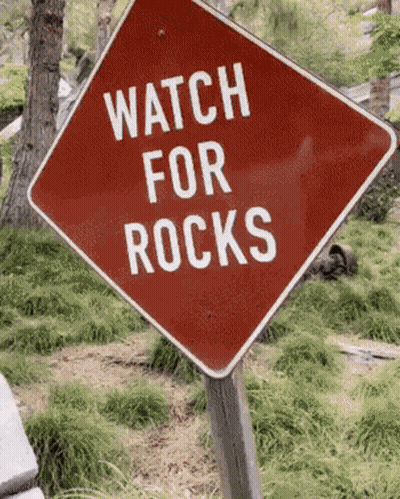 Red Sign Saying Watch For Rocks GIF