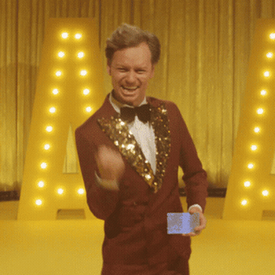 Red-Suited Bow-Tied Man Holding Card Near Large A GIF