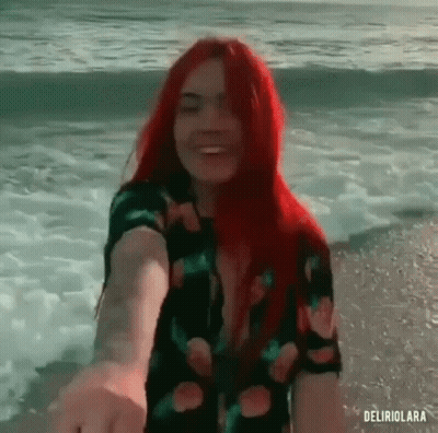 Redhead Woman Holding Man's Hand On Beach GIF