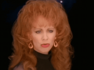 Redhead Woman In Black Turtleneck Making Funny Face GIF