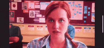 Redhead Woman Sitting In Front Of Bulletin Board GIF
