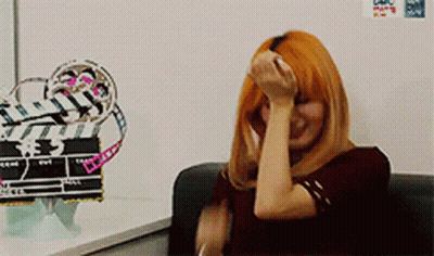 Redhead Woman Sitting In Front Of White Board With Sticker GIF