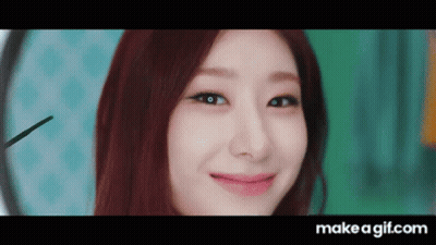 Redhead Woman Smiling In Front Of Clock GIF