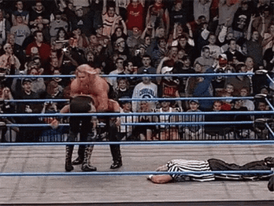 Referee Lying In Ring As Wrestler Jumps Over Him GIF