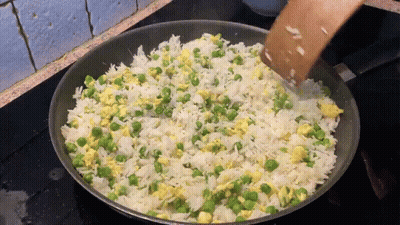 Rice And Peas Are Being Stirred In A Frying Pan GIF