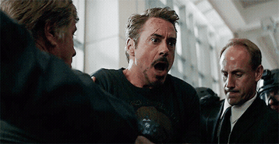 Robert Downey Jr. Is Being Held By A Group Of Men While Wearing A Black T-Shirt . GIF