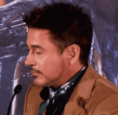 Robert Downey Jr. Is Talking Into A Microphone While Wearing A Suit And Tie . GIF