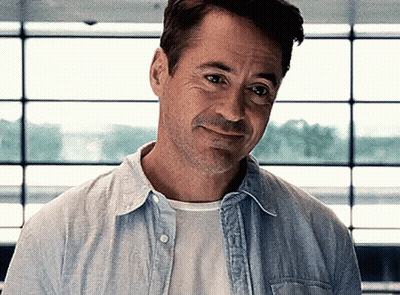 Robert Downey Jr. Is Wearing A Blue Shirt And White T-Shirt And Smiling . GIF