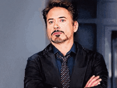 Robert Downey Jr. Is Wearing A Suit And Tie With His Arms Crossed And A Beard . GIF