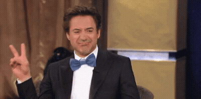 Robert Downey Jr. Is Wearing A Tuxedo And Bow Tie And Making A Peace Sign . GIF