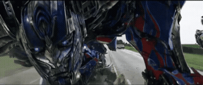 Robot Walking Down Road With Car Behind GIF