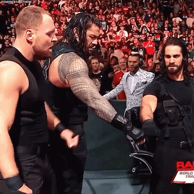 Roman Reigns And Seth Rollins Are Shaking Hands During A Wrestling Match . GIF