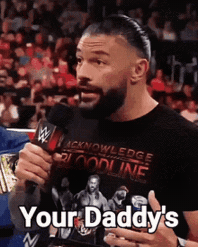 Roman Reigns Is Holding A Microphone And Saying `` Your Daddy 'S '' While Wearing A Black Shirt . GIF
