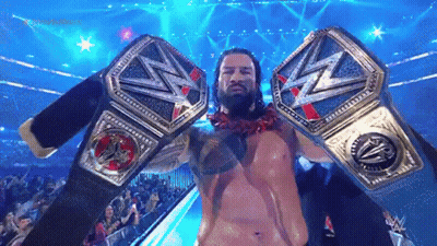 Roman Reigns Is Holding Two Wrestling Championship Belts In His Hands . GIF
