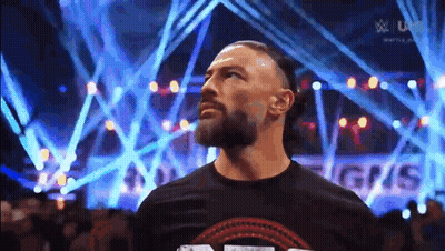 Roman Reigns Is Standing In Front Of A Crowd Of People In A Stadium . GIF