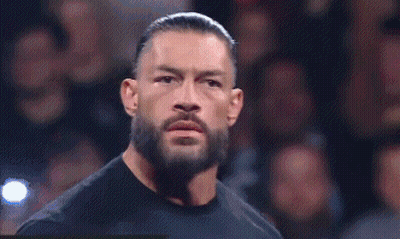 Roman Reigns Is Standing In Front Of A Crowd Wearing A Black Shirt . GIF
