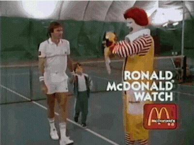 Ronald Mcdonald Is Standing On A Tennis Court With A Tennis Player GIF