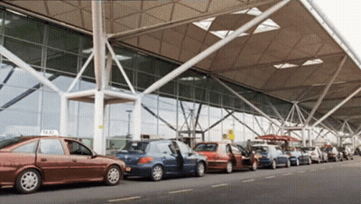 Row Of Cars Parked By Building With Taxi Sign GIF