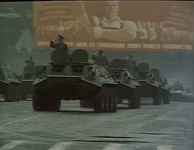 Row Of Military Vehicles In Front Of Russia Billboard GIF