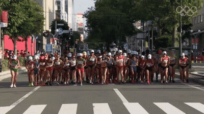 Runners Running Down Street With Olympic Rings GIF