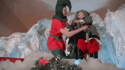 Santa Assistant Putting Kid On Slide GIF