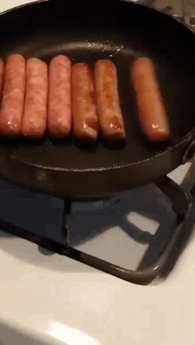 Sausages Are Cooking In A Frying Pan On A Stove Top GIF