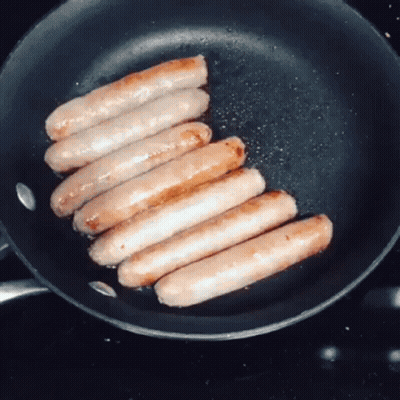 Sausages Are Cooking In A Frying Pan On The Stove GIF