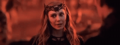 Scarlet Witch Is Wearing A Crown On Her Head And Looking At A Man In A Dark Room . GIF