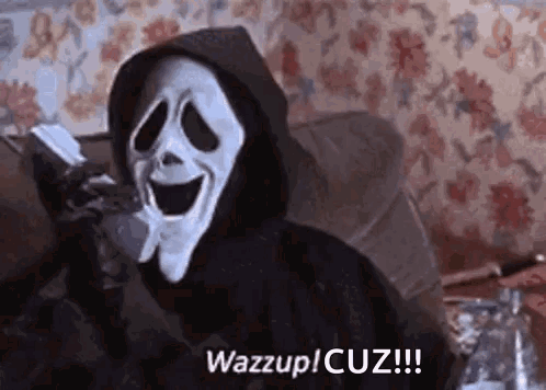 Scream Is Sitting On A Couch Wearing A Hooded Jacket And A Mask . GIF