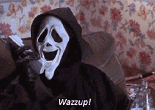 Scream Is Talking On A Cell Phone While Wearing A Hooded Cape . GIF