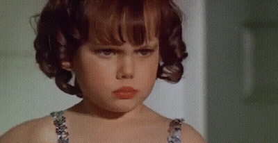 Serious Young Girl With Curly Hair Looking At Camera GIF