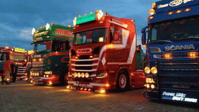 Several Scania Trucks Are Parked In A Row At Night GIF
