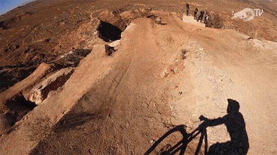 Shadow Of Person Riding Bike On Dirt Road With Red Bull TV Logo GIF