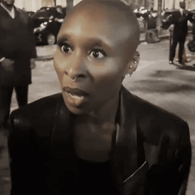 Shaved Head Woman In Earrings And Black Jacket GIF