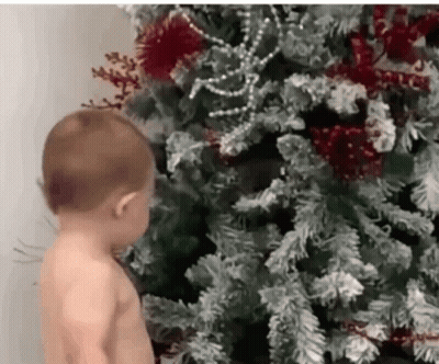 Shirtless Baby Next To Christmas Tree GIF