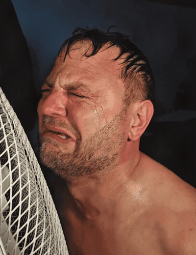 Shirtless Bearded Man Crying in Front of White Fan